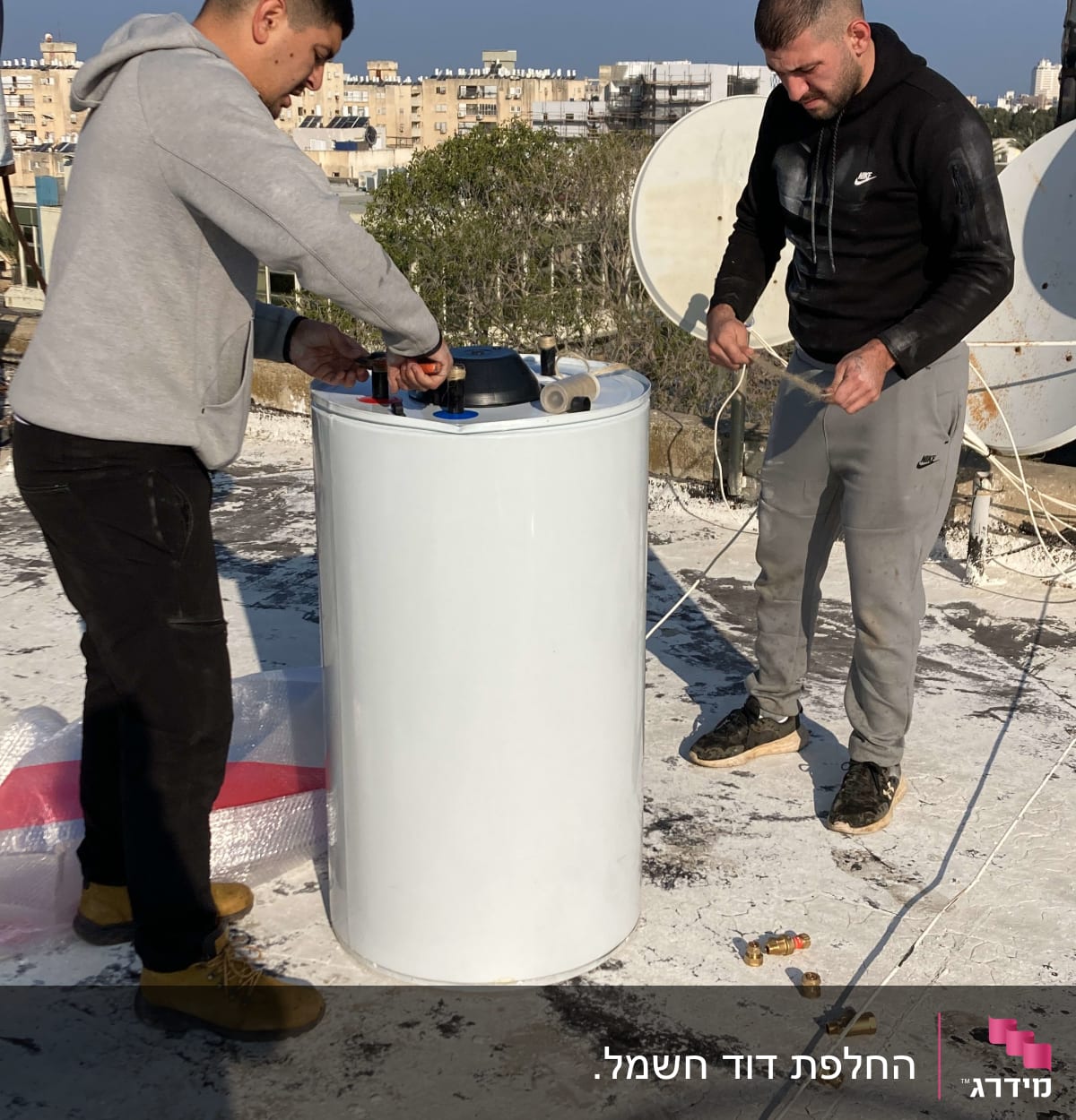 שני אנשים מתקינים דוד שמש על גג